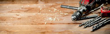 Drill with drills on the table. On a wooden background. High quality photo