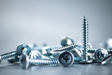 A bunch of self-tapping screws on the table. On a gray background. High quality photo