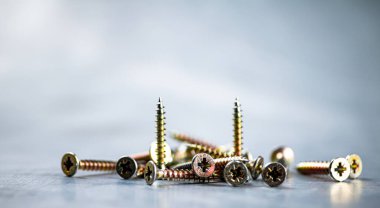 A bunch of self-tapping screws on the table. On a gray background. High quality photo