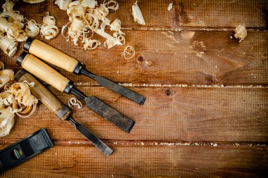 Chisels with wooden sawdust on the table. On a wooden background. High quality photo