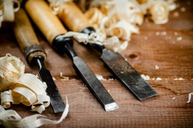 Chisels with wooden shavings. On a wooden background. High quality photo