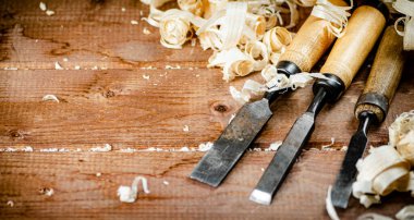 Chisels with wooden shavings. On a wooden background. High quality photo