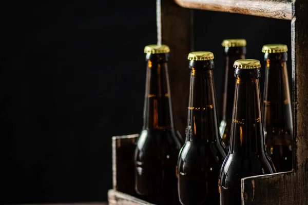 stock image Beer bottles in an old box. On wooden background.