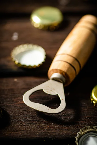 stock image Opener with beer caps. On wooden background.