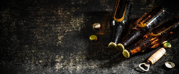 stock image Beer bottles with opener. On rustic background.