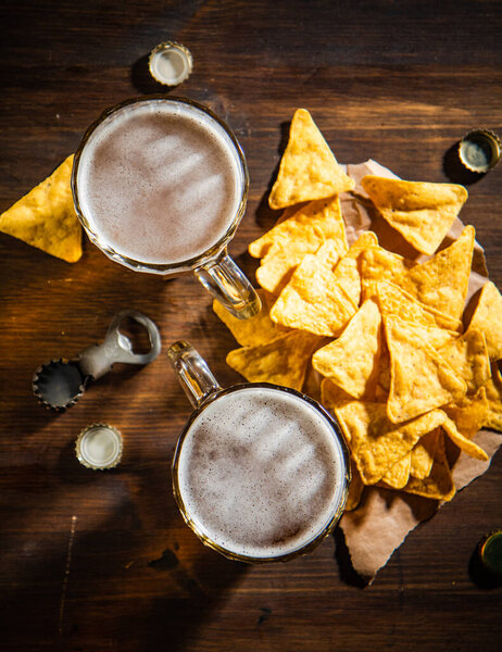 Fresh beer with corn chips. On rustic background.