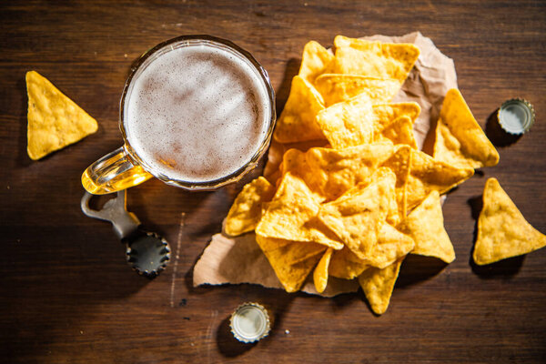 Fresh beer with corn chips. On rustic background.
