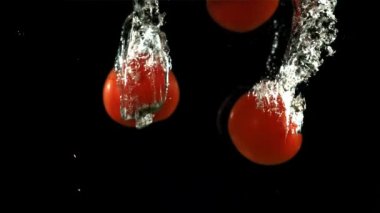 Domatesler suyun altına düşer. Film, yavaş çekim 1000 fp. Yüksek kaliteli FullHD görüntüler