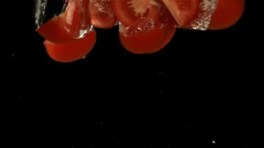 Domates dilimleri suya düşer. Film, yavaş çekim 1000 fp. Yüksek kaliteli FullHD görüntüler