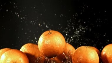 Portakallar su damlalarıyla uçar. Film, yavaş çekim 1000 fp. Yüksek kaliteli FullHD görüntüler
