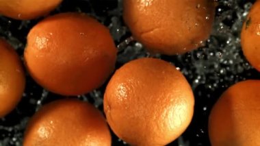 Portakallar su damlalarıyla uçar. Film, yavaş çekim 1000 fp. Yüksek kaliteli FullHD görüntüler