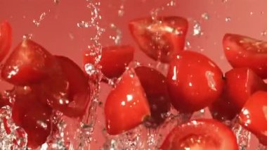 Domates dilimleri su damlalarıyla uçar. Film, yavaş çekim 1000 fp. Yüksek kaliteli FullHD görüntüler