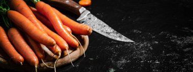 Kesme tahtasındaki havuçlar. Siyah bir masada..