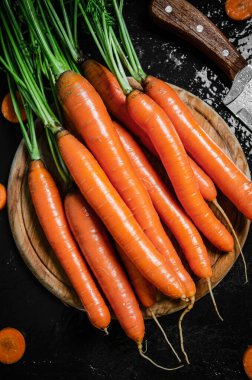 Kesme tahtasındaki havuçlar. Siyah bir masada..