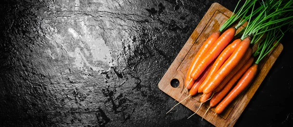 Carrots on a cutting board. On a black table.
