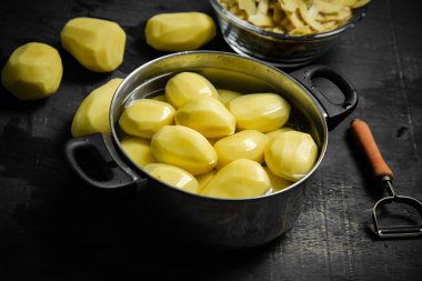 Taze soyulmuş patates. Siyah bir arkaplanda.