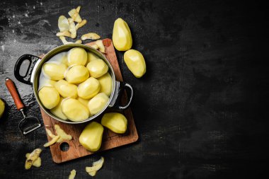 Taze soyulmuş patates. Siyah bir arkaplanda.