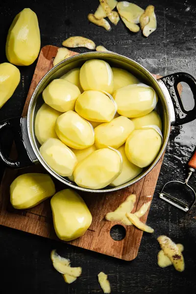 Taze soyulmuş patates. Siyah bir arkaplanda.