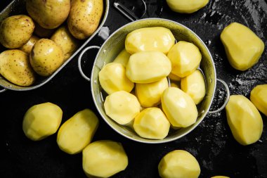 Taze soyulmuş patates. Siyah bir arkaplanda.