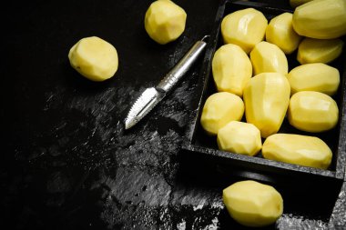 Taze soyulmuş patates. Siyah bir arkaplanda.