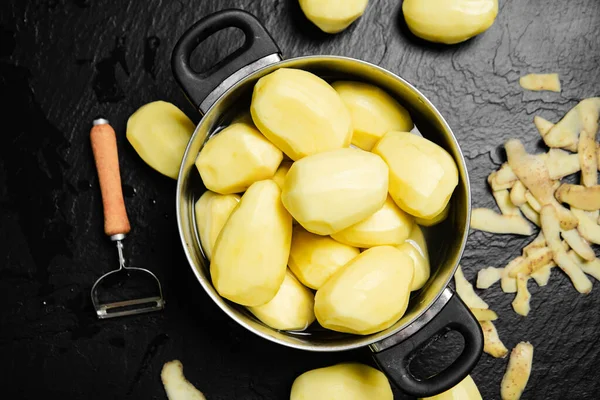 Taze soyulmuş patates. Siyah bir arkaplanda.