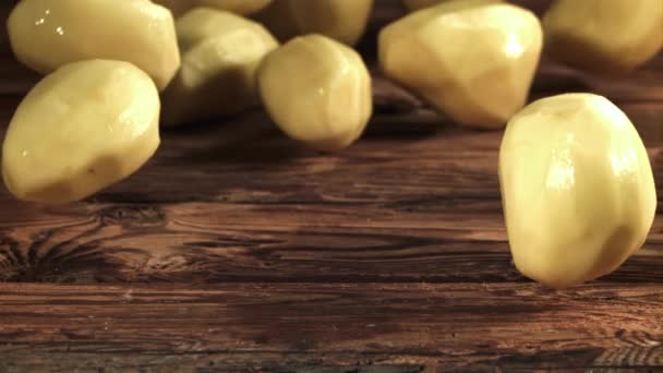 Geschilde Aardappelen Rollen Een Houten Tafel Gefilmd Een Hoge Snelheidscamera — Stockvideo