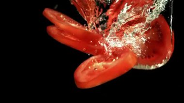 Dilimlenmiş domatesler suya düşer. 1000 fps 'de yüksek hızlı bir kamerayla çekildi. Yüksek kaliteli FullHD görüntüler