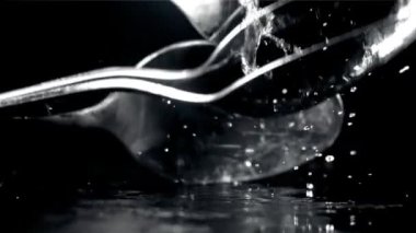Kaşıklar ıslak siyah bir masaya düşer. 1000 fps 'de yüksek hızlı bir kamerayla çekildi. Yüksek kaliteli FullHD görüntüler