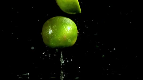 Limes Vallen Een Zwarte Natte Tafel Gefilmd Een Hoge Snelheidscamera — Stockvideo