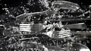 Çatal bıçak takımı su damlatarak uçuyor. Yukarıdan bak. 1000 fps 'de yüksek hızlı bir kamerayla çekildi. Yüksek kaliteli FullHD görüntüler