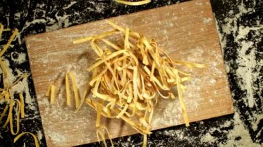 Ev yapımı fettucine makarna kesim tahtasına düşer. Yukarıdan bak. Yüksek kaliteli FullHD görüntüler