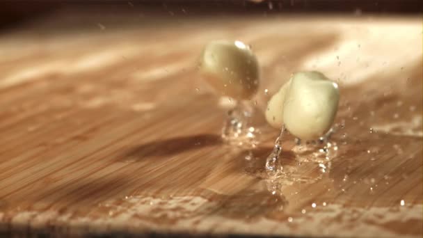 Frischer Knoblauch Fällt Auf Ein Nasses Schneidebrett Gefilmt Mit Einer — Stockvideo