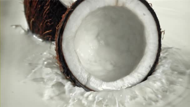 Die Hälfte Der Kokosnuss Fällt Mit Spritzern Die Milch Gefilmt — Stockvideo