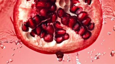 Fışkıran su taze nara dökülür. 1000 fps 'de yüksek hızlı bir kamerayla çekildi. Yüksek kaliteli FullHD görüntüler