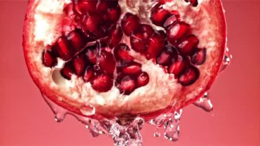 Fışkıran su taze nara dökülür. 1000 fps 'de yüksek hızlı bir kamerayla çekildi. Yüksek kaliteli FullHD görüntüler