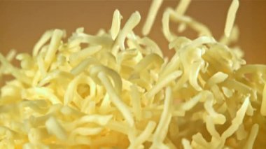 Rendelenmiş peynir yukarı uçar ve düşer. Turuncu arka planda. 1000 fps 'de yüksek hızlı bir kamerayla çekildi. Yüksek kaliteli FullHD görüntüler