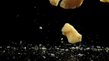 Siyah arka plana parmesan peyniri dökülüyor. 1000 fps 'de yüksek hızlı bir kamerayla çekildi. Yüksek kaliteli FullHD görüntüler