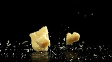 Siyah arka plana parmesan peyniri dökülüyor. 1000 fps 'de yüksek hızlı bir kamerayla çekildi. Yüksek kaliteli FullHD görüntüler