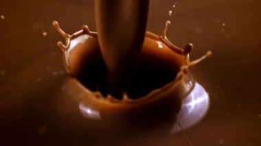 Süper yavaş çekimde bir sıcak çikolata akıntısı su sıçratarak içeri doluyor. Yüksek kaliteli FullHD görüntüler