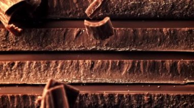 Çikolata dilimlerinin üzerinde sütlü çikolatanın süper yavaş düşüşü. Yüksek kaliteli FullHD görüntüler