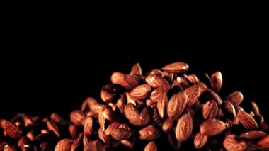 Bir eğlence etkinliği, siyah arka planda bir yığın badem sergiliyor. Karanlık ve ahşap aksanlı, natürmort bir fotoğrafçılıkla çekiliyor. Yemek ve sanatın mükemmel bir karışımı.