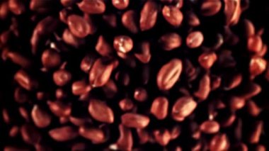 Siyah arka plana istiflenmiş fıstıkları yakın plan, bir model oluşturur. Bitki ve karmine fındıkları arasındaki zıtlık çarpıcı bir görüntü yaratır.