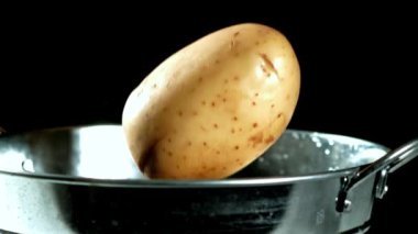 Süper yavaş çekim patatesleri bir kova suya düşer. Yüksek kaliteli FullHD görüntüler