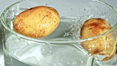 Süper yavaş hareket eden patatesler su damlatarak suya düşüyorlar. Yüksek kaliteli FullHD görüntüler