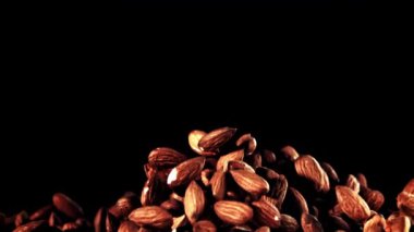 Büyüleyici makro fotoğrafçılık koyu arkaplana düşen bir yığın badem yakalıyor ve görsel olarak çarpıcı bir görüntü yaratıyor.