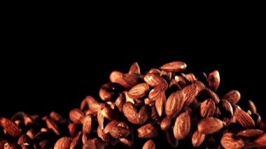 Bir eğlence etkinliği, siyah arka planda bir yığın badem sergiliyor. Karanlık ve ahşap aksanlı, natürmort bir fotoğrafçılıkla çekiliyor. Yemek ve sanatın mükemmel bir karışımı.