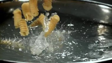 Makarna kaynar suya dökülüyor. 1000 fps 'de yüksek hızlı bir kamerayla çekildi. Yüksek kaliteli FullHD görüntüler