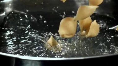 Makarna kaynar suya dökülüyor. 1000 fps 'de yüksek hızlı bir kamerayla çekildi. Yüksek kaliteli FullHD görüntüler