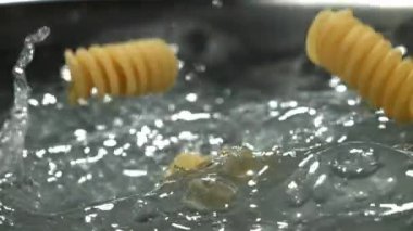 Fusilli makarna kaynayan suya düşer. 1000 fps 'de yüksek hızlı bir kamerayla çekildi. Yüksek kaliteli FullHD görüntüler