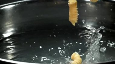 Fusilli makarna kaynayan suya düşer. 1000 fps 'de yüksek hızlı bir kamerayla çekildi. Yüksek kaliteli FullHD görüntüler